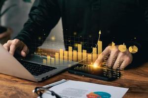 homme d'affaires travaillant avec un tableau de bord virtuel pour ordinateur portable et smartphone analysant les données de ventes financières et le graphique de croissance économique. photo