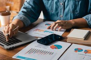 notion comptable. homme d'affaires travaillant à l'aide d'un ordinateur portable avec analyse des données de ventes financières et du graphique de croissance économique. au café. photo