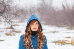 jeune femme en manteau bleu rétro à pied dans le parc brumeux en hiver, fond de neige et d'arbres, concept de fantaisie ou de fée