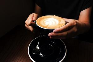 café au lait dans sa main. fond sombre photo