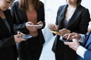 groupe de jeunes gens d'affaires debout et utilisant un smartphone ensemble des concepts de communication. photo