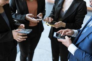 groupe de jeunes gens d'affaires debout et utilisant un smartphone ensemble des concepts de communication. photo