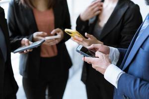 groupe de jeunes gens d'affaires debout et utilisant un smartphone ensemble des concepts de communication. photo