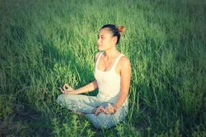 yoga dans la ville belle jeune femme en forme portant des vêtements de sport méditant, respirant, assise avec les jambes croisées en posture de demi-lotus dans la rue le jour d'été, ardha padmasana, espace de copie photo