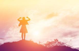 femme heureuse sautant contre le beau coucher de soleil. liberté, concept de plaisir. photo