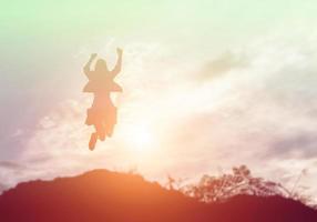 femme heureuse sautant contre le beau coucher de soleil. liberté, concept de plaisir. photo