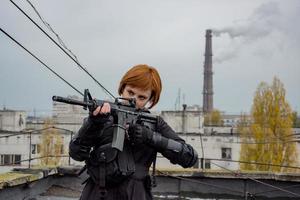 jeune femme dans un style techwear noir moderne avec un fusil posant sur le toit, portrait d'une femme rousse cyperpunk ou concept post-apocalyptique photo