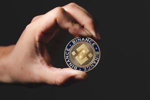 la main ou les doigts ramassent la pièce de monnaie binance bnb incluse avec la monnaie crypto dans l'ombre symbole de la salle noire l'avenir de la technologie de la blockchain virtuelle est l'argent numérique en gros plan et en macro.