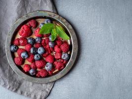 bleuets et framboises sur assiette. un mélange de baies sur fond sombre, copiez l'espace. photo