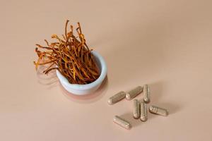 mycélium cordyceps militaris sec dans un bol blanc avec fond en bois. champignon médical orange pour une bonne santé. photo