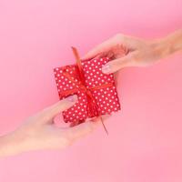 deux femmes tenant un cadeau dans une boîte cadeau rouge avec un arc, le passant de l'une à l'autre, photo