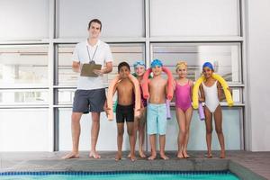 entraîneur de natation avec ses élèves au bord de la piscine
