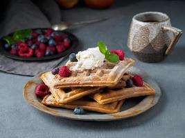 gaufres belges aux framboises, sirop de chocolat. petit déjeuner avec thé sur fond sombre, vue latérale photo