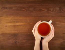 femme tenant une tasse de thé sur fond de bois foncé vue de dessus copie espace photo