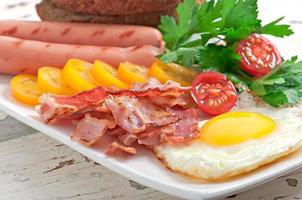 petit-déjeuner anglais - œufs au plat, bacon, saucisses et pain de seigle grillé photo