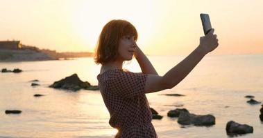 jeune femme en robe de détente sur la plage d'été avec téléphone portable photo