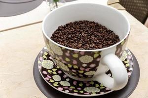 graines de café dans une grande tasse en céramique sur un fond de table. tas de grains de café dans une tasse. photo