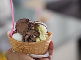 chocolat, thé thaï à l'orange, glace au lait de coco dans une tasse de gaufre croustillante dans la main de la femme photo