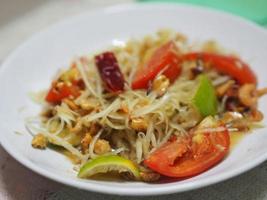 salade de papaye verte avec piment tomate et ail, ajouter des crevettes servies avec des légumes sur la table, goût de la cuisine thaïlandaise aigre-douce épicée salée photo