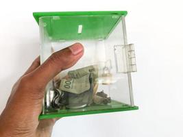 photo de mains tenant une boîte de charité remplie de papier-monnaie