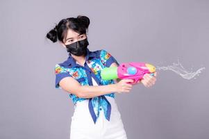 de belles femmes asiatiques portent un masque chirurgical tout en tenant un pistolet à eau en plastique pendant le festival de songkran photo