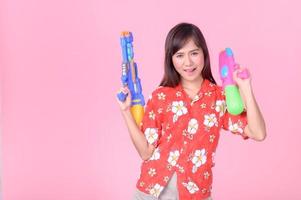 une belle femme asiatique montre un geste tout en tenant un pistolet à eau en plastique pendant le festival de songkran photo