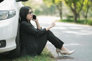 une jeune femme asiatique appelle son technicien de service pour réparer une voiture cassée sur le bord de la route photo