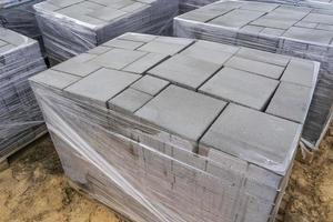 pose de dalles en béton gris dans le patio de l'allée de la cour de la maison. les maçons professionnels installent de nouvelles tuiles ou dalles pour l'allée, le trottoir ou le patio sur une fondation sablonneuse plate. photo