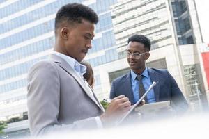 des hommes d'affaires se réunissent pour parler et partager leurs idées en ville. équipe commerciale et concept de travail d'équipe. des hommes d'affaires debout à l'extérieur de la ville discutant d'un nouveau projet. photo