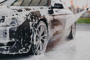 processus de lavage de voiture professionnel avec détergent chimique et nettoyeur haute pression photo