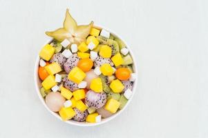 vue de dessus de fruits exotiques frais dans un bol. morceaux de fruit du dragon blanc, kiwi, pitaya, mangue et carambole. dessert végétarien savoureux pour manger photo
