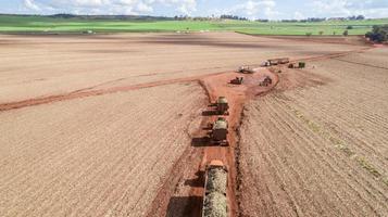 vue aérienne de trois tracteurs avec débordement chargeant la canne à sucre récoltée par la machine. photo