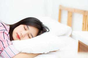 portrait d'une belle jeune femme asiatique dormir au lit avec la tête sur l'oreiller confortable et heureux avec les loisirs, fille avec détente pour le concept de santé et de style de vie. photo