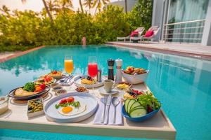 petit-déjeuner dans la piscine, petit-déjeuner flottant dans un luxueux complexe tropical. table relaxante sur l'eau calme de la piscine, petit-déjeuner sain et assiette de fruits au bord de la piscine du complexe. style de vie de luxe de plage tropicale