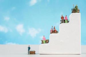 personnes miniatures. un petit homme d'affaires assis sur un tas de pièces de monnaie, financier, concept de croissance d'entreprise. photo