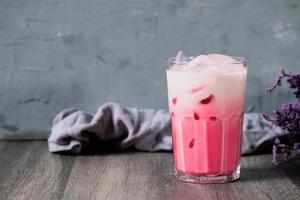 boisson froide au lait rose froid en verre clair sur fond gris. lait thaïlandais photo