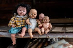 un groupe de poupées assises dans une vieille maison en bois. photo