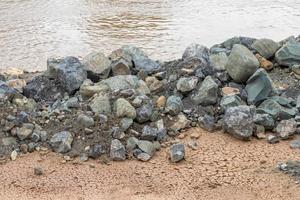 tas de granit sur le sol près de la rive du fleuve. photo