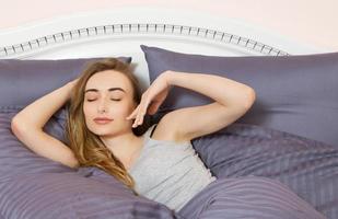 belle jeune femme se réveillant dans une chambre rose foncé photo