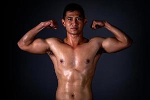 un homme asiatique fort a levé les bras pour montrer ses muscles forts et beaux de l'exercice