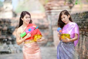 de belles femmes asiatiques tiennent des pistolets à eau en plastique dans un ancien temple pendant songkran, le festival de l'eau le plus beau et le plus amusant de thaïlande photo