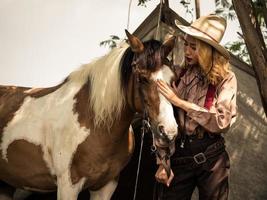 cowgirl touche le cheval avec amour à cause de relations qui sont des amis qui partagent la souffrance et le bonheur ensemble photo