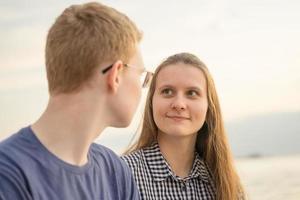 fille regardant un garçon sur une plage au coucher du soleil, concept d'amour chez les adolescentes photo