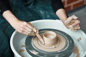 femme faisant de la poterie en céramique sur roue, mains en gros plan, création d'articles en céramique