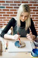 femme faisant un motif sur une plaque en céramique avec un pinceau. concept de passe-temps créatif. gagner de l'argent supplémentaire, agitation latérale, transformer les loisirs en argent, la passion en travail, vertical