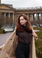 belle fille heureuse à la mode coquine drôle dansant dans les rues de st. ville de pétersbourg. charmante femme souriante aux longs cheveux noirs, verticale photo