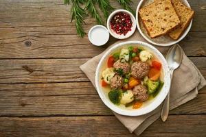 soupe de boulettes de viande dans une assiette blanche sur une vieille table grise rustique en bois, vue de dessus photo