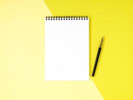 bloc-notes vierge page blanche sur le bureau jaune, fond de couleur. vue de dessus, espace vide pour le texte.