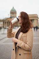 belle fille intelligente à la mode élégante et sérieuse boit du café, va marcher dans la rue de st. Saint-Pétersbourg dans le centre-ville. charmante femme réfléchie aux longs cheveux noirs photo