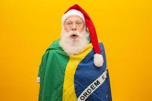 le père noël est un fan du brésil. supporter du père noël de l'équipe brésilienne. championnat sportif. père noël tenant le drapeau brésilien. match de football. photo